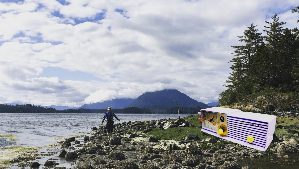 Stacey standing on a river shore, surrounded by Canadian woods with mountains going into the clouds in the background.